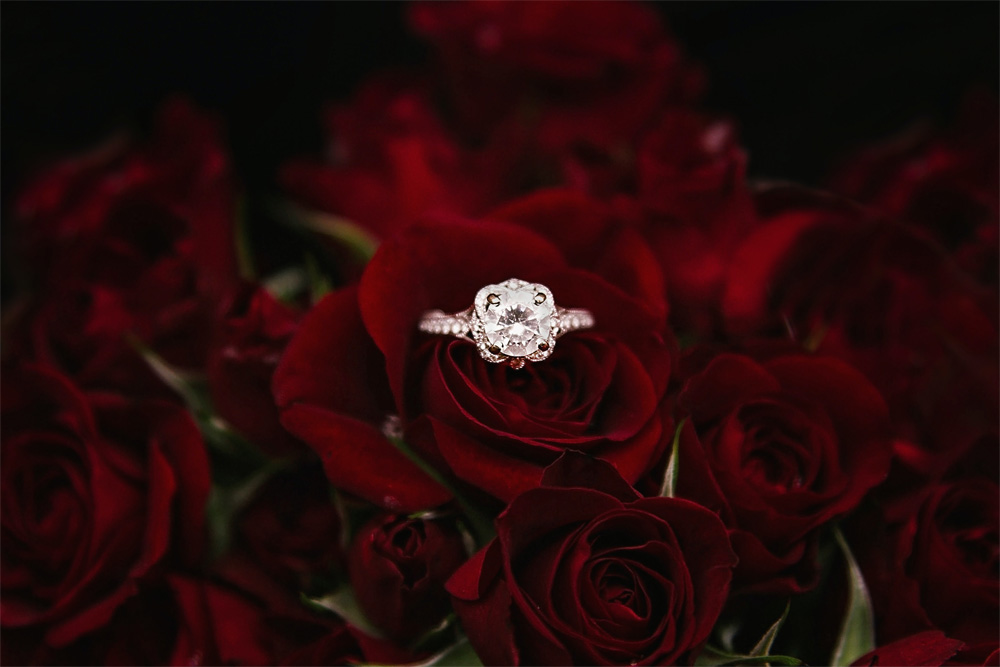a diamond ring sitting amongst many red roses
