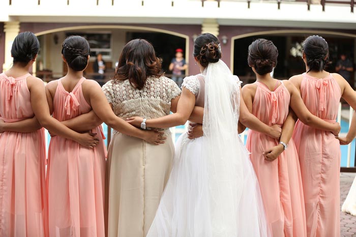 back view of bride and bridesmaids with arms around each other