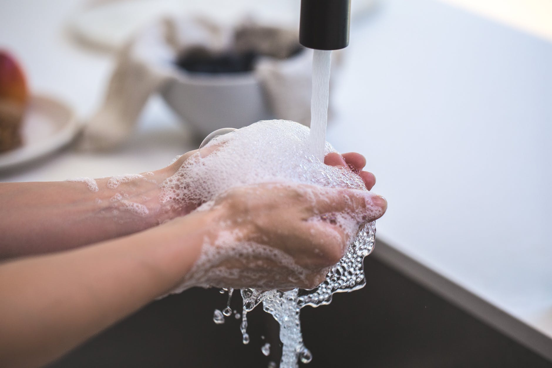 close-up of person washing hands in kitchen sink