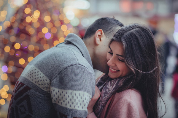 couple hugging in front of a christmas tree