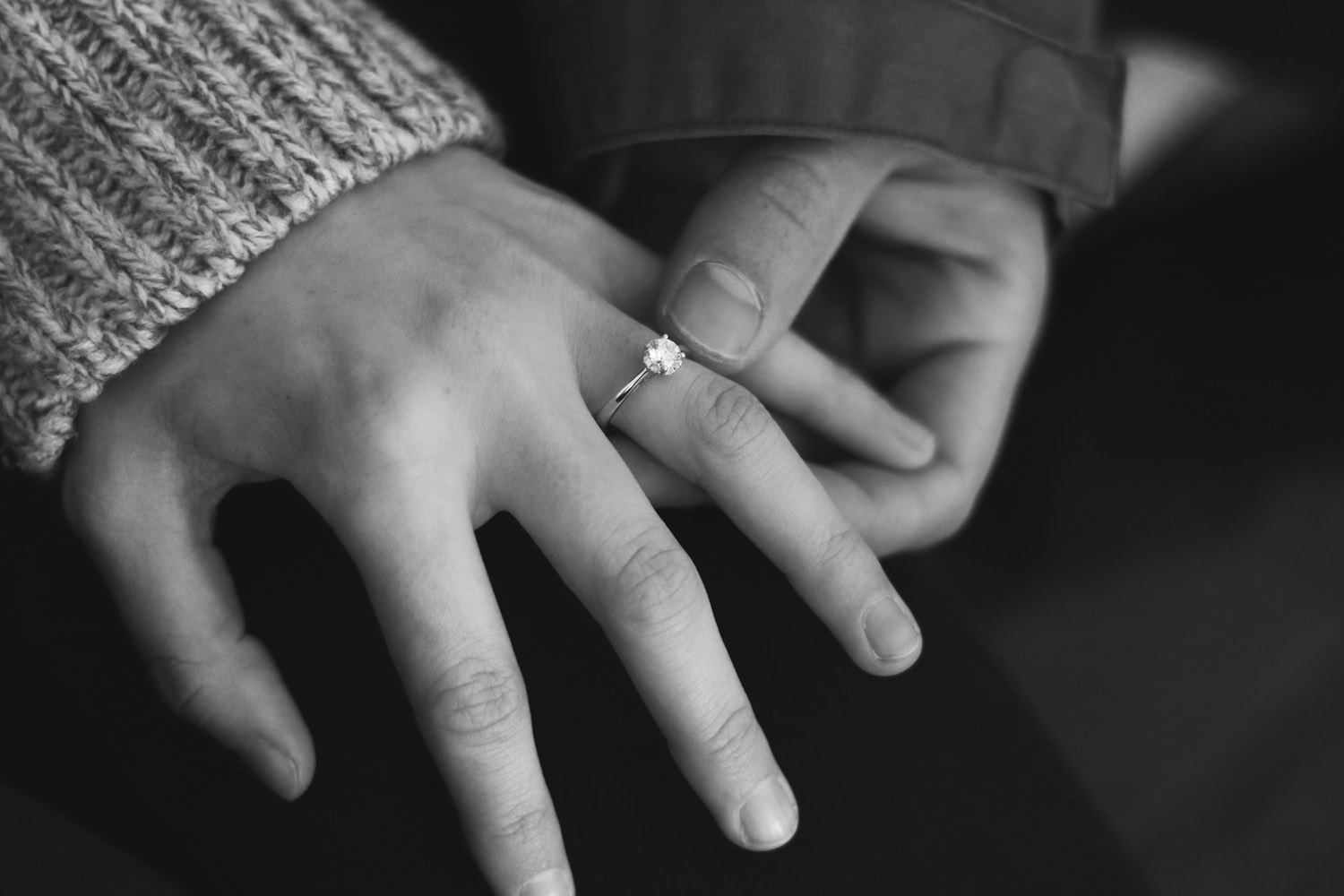 man holding a woman’s hand with an engagement ring on