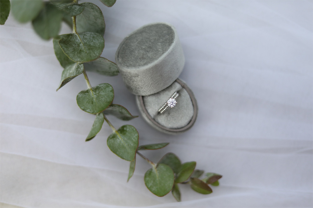 engagement ring and wedding band in a sage green ring box