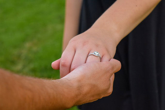 woman with ring holding man’s hand