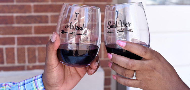 close-up of woman wearing engagement ring toasting fiance with wine