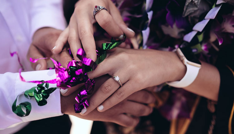 close-up of hands wearing engagement ring holding ribbons