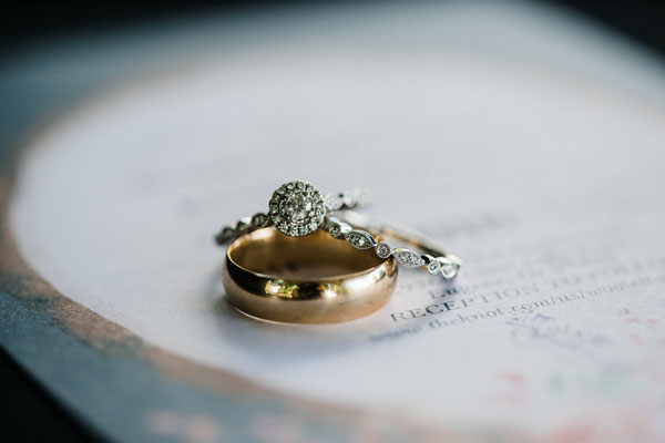 women’s rose gold and diamond ring and men’s carved band on a flower