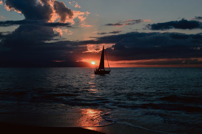 sunset over a sailboat at sea