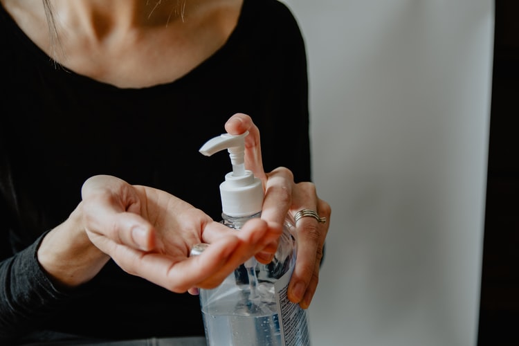 woman in black shirt applying hand sanitizer from pump bottle