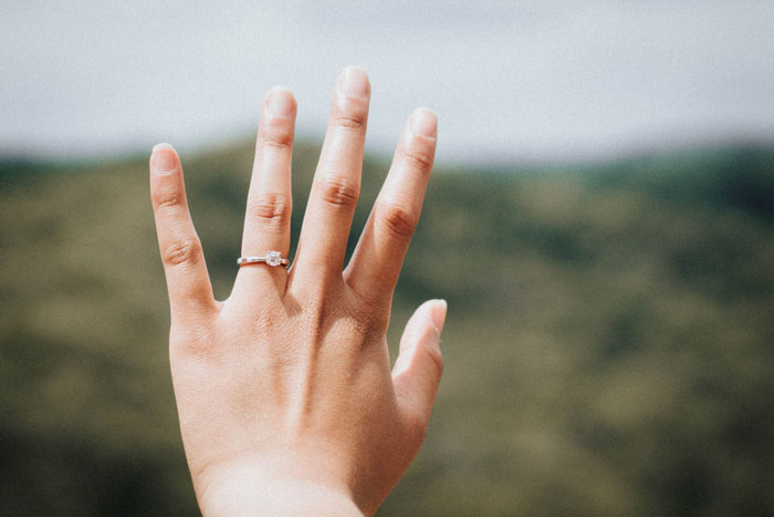 a person’s hand with an engagement ring